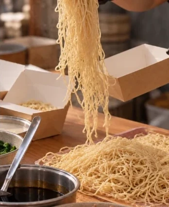 Mie segar menjuntai di atas kotak Warisan Rasa